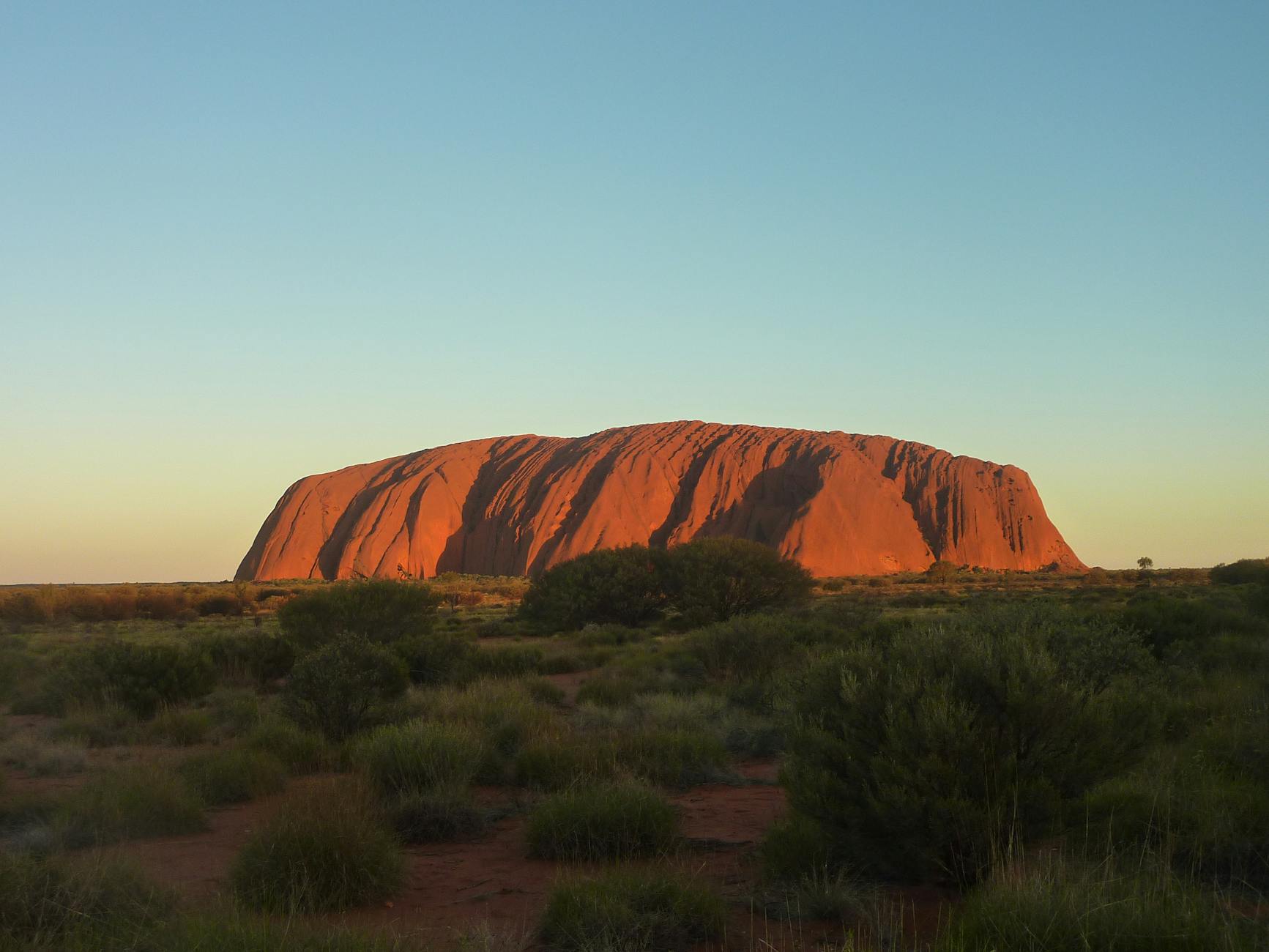 Uluru o zachodzie słońca, pomarańczowa skała na tle pustynnego Outbacku