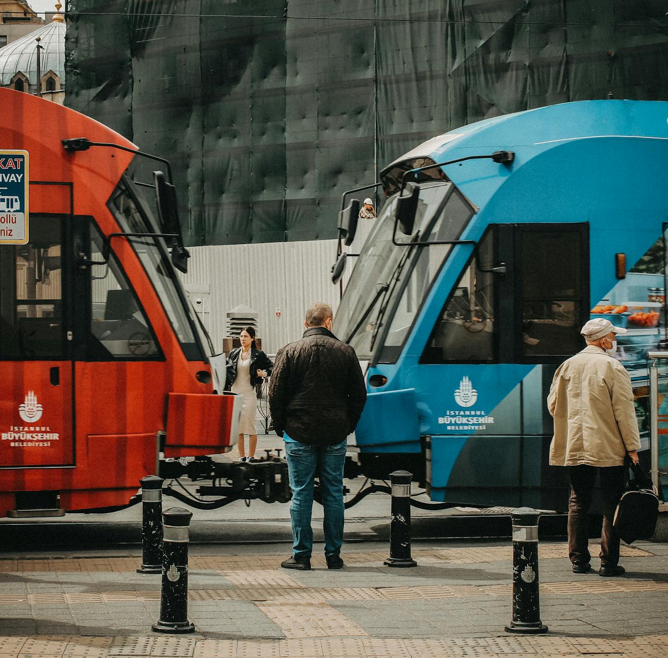 Czerwony i niebieski tramwaj mijają się na ruchliwej ulicy w Stambule
