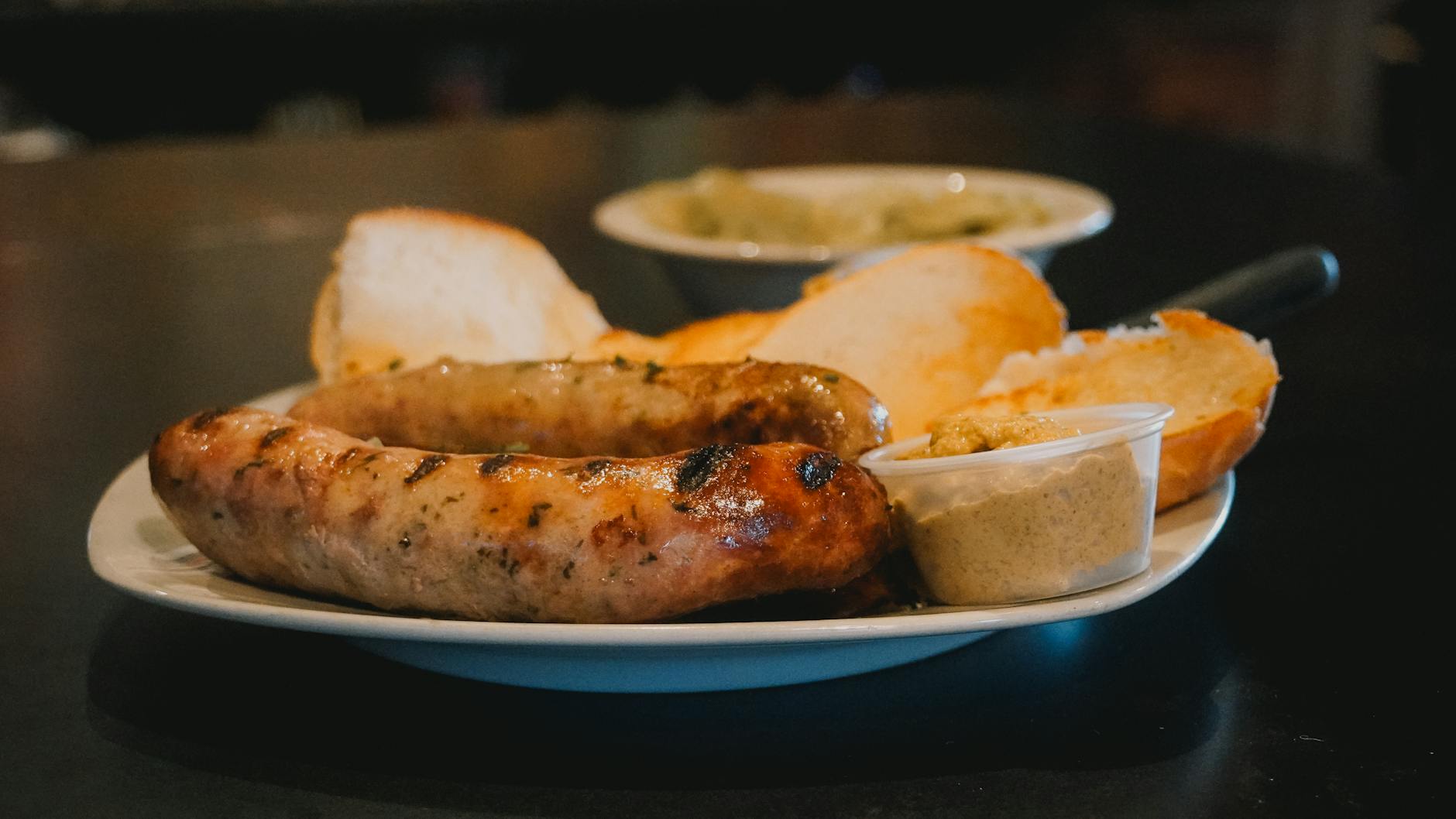 Grillowane niemieckie kiełbaski z pieczywem i musztardą na talerzu