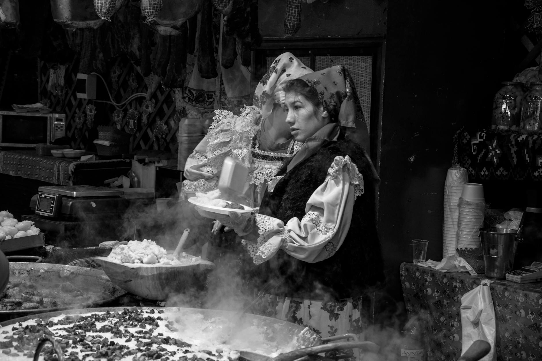 Kobieta w stroju ludowym przygotowuje rumuńskie jedzenie na targu w Timișoarze