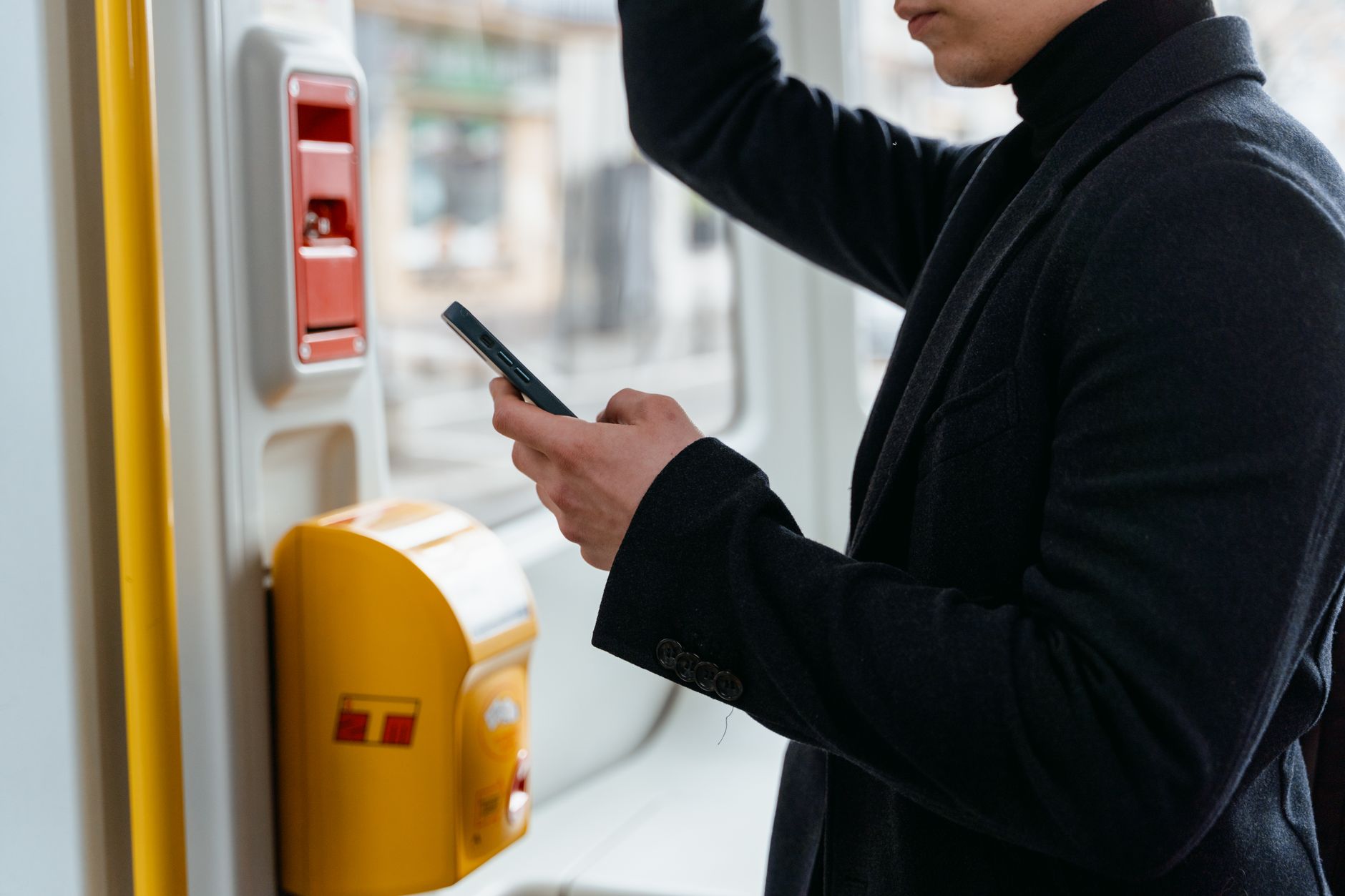 Podróżny w czarnym płaszczu sprawdza bilety kolejowe w telefonie