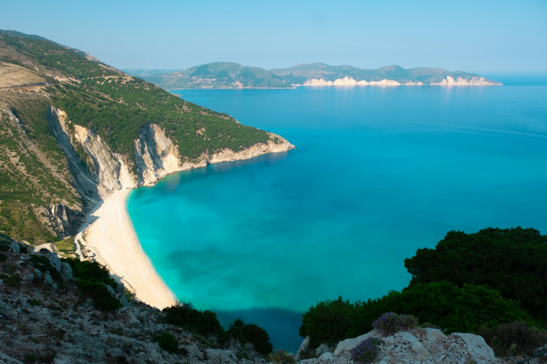 Turkusowa zatoka z piaszczystą plażą i klifami na greckiej wyspie